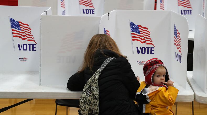 Contour Sanford, 18-months, looks around the gym at Tecumseh High School as his mother, Erin, casts her vote Tuesday. BILL LACKEY/STAFF