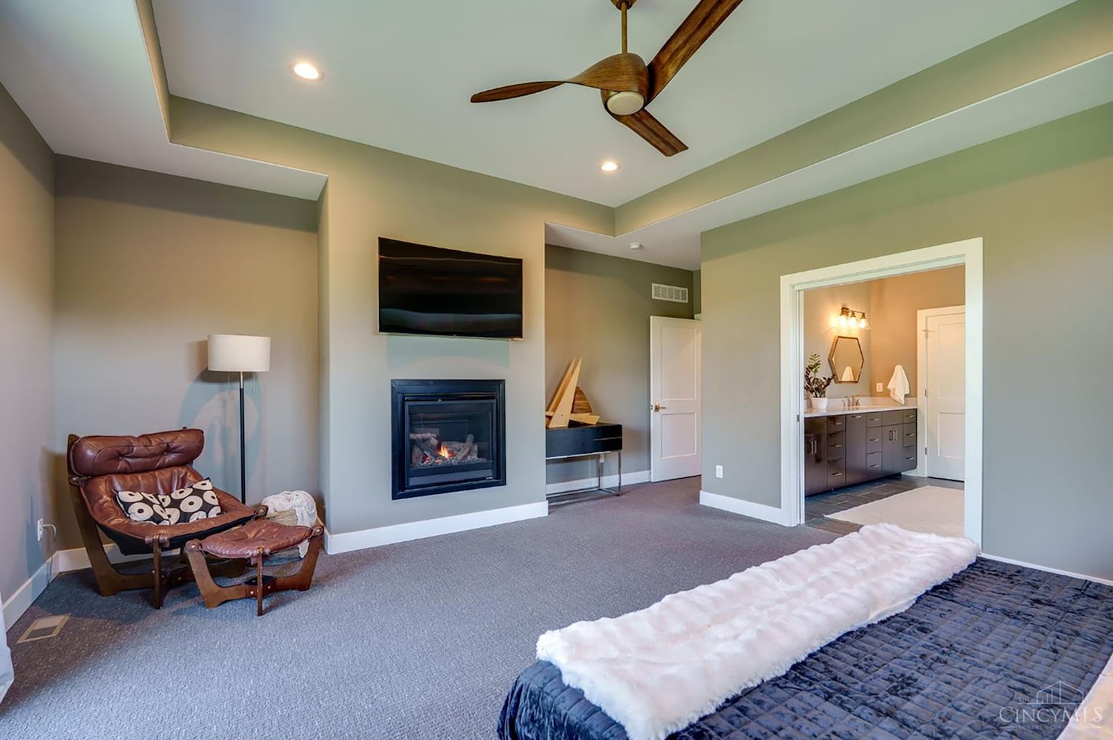 The primary suite is on the main floor and is carpeted, has a tray ceiling and recessed lighting and a ceiling fan as well as a gas fireplace. CONTRIBUTED