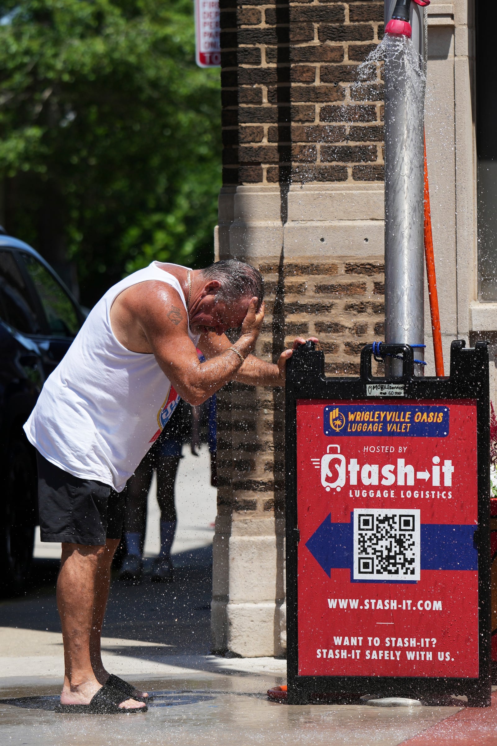 A man cools off under a sprinkler provided by a Chicago Fire Department during hot weather in Chicago, Sunday, June 22, 2025. (AP Photo/Nam Y. Huh)