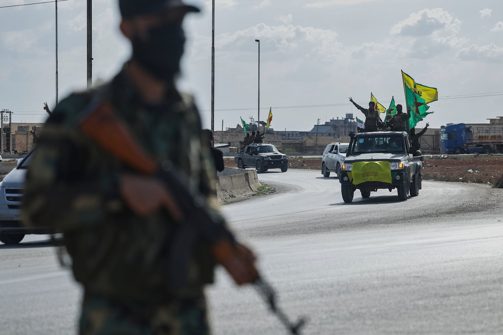 U.S.-backed Kurdish fighters stands on their vehicles, as they withdraw from two neighborhoods in Syria's northern city of Aleppo as part of a deal with the Syrian central government, in Aleppo, Syria, Friday, April 4, 2025. (AP Photo/Ghaith Alsayed)