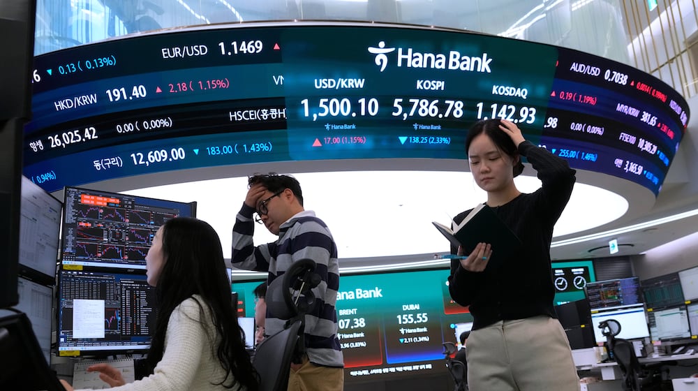 Currency traders work near a screen showing the Korea Composite Stock Price Index (KOSPI), top center, and the foreign exchange rate between U.S. dollar and South Korean won, top center left, at the foreign exchange dealing room of the Hana Bank headquarters in Seoul, South Korea, Thursday, March 19, 2026. (AP Photo/Ahn Young-joon)