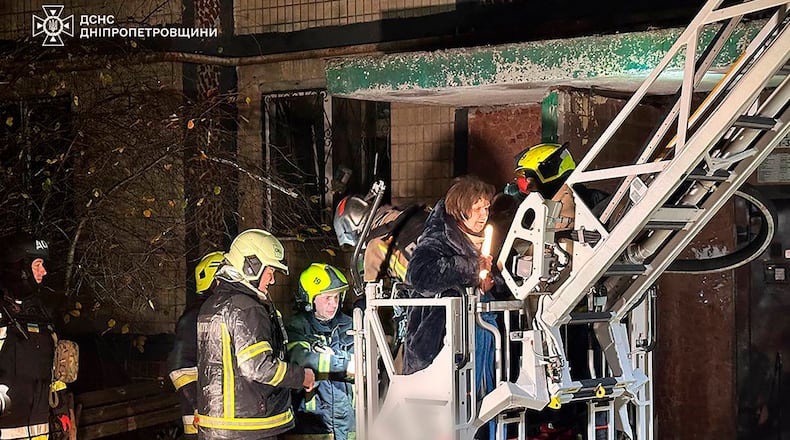 In this photo provided by the Ukrainian Emergency Service, firefighters evacuate a resident following a Russian rocket attack that hit a multi-storey apartment building in Dnipro, Ukraine, Saturday, Nov. 8, 2025. (Ukrainian Emergency Service via AP)