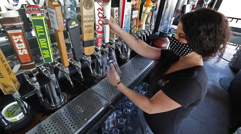 Nikki Callicoat pours a draft beer behind the bar at O'Conner's Irish Pub Friday. BILL LACKEY/STAFF