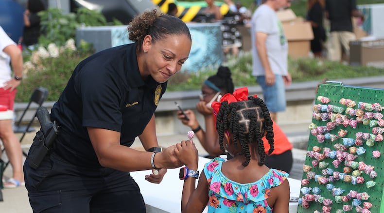 Springfield Police Officer Amanda Jackson gives a young girl a piece of candy for winning a game during the National Night Out in Springfield Tuesday, August 2, 2022. City leaders want to increase police hiring in 2023 under the proposed budget. BILL LACKEY/STAFF