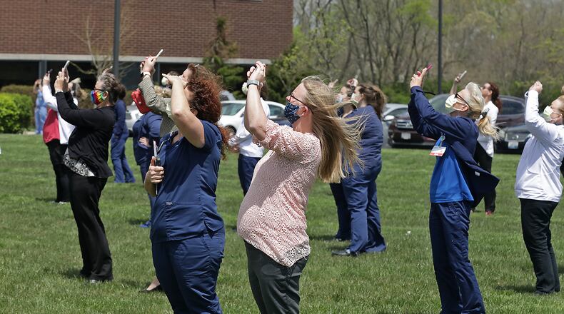 The staff at Mercy Health's Springfield Regional Medical Center gather on the front lawn of the hospital Thursday to watch two Ohio Air National Guard F-16's perform a fly-over as a salute to Ohio health care workers, first responders, military members and other essential personnel. BILL LACKEY/STAFF