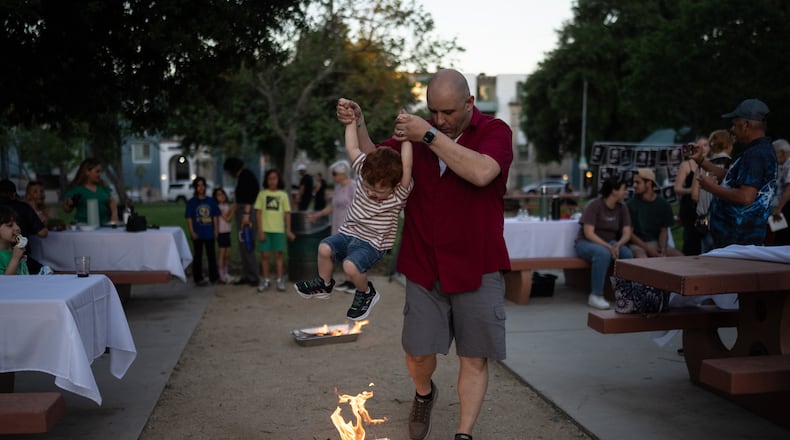 Sohrab Yassan lifts his son over a small fire as they participate in Chaharshanbe Suri, a traditional festival leading up to the Nowruz holiday, during a community gathering in the Encino neighborhood of Los Angeles, March 17, 2026. (AP Photo/Jae C. Hong)