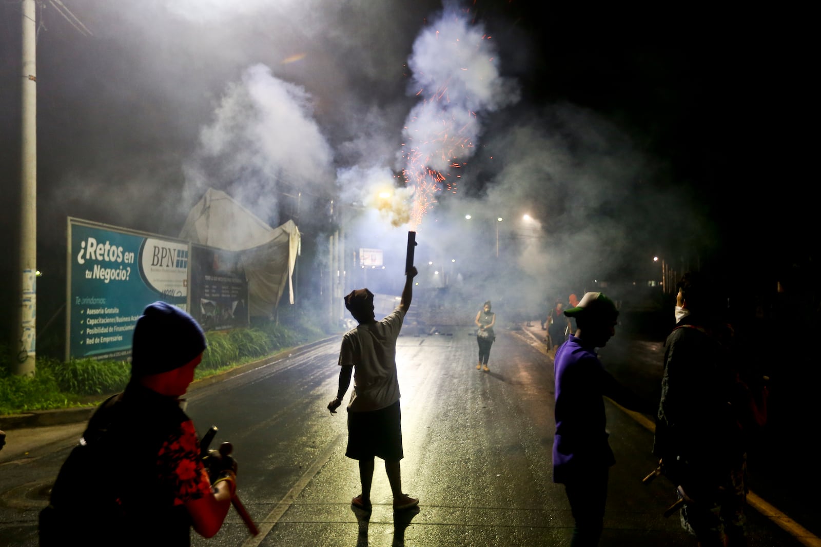 FILE - A university student fires a homemade mortar in honor of high school student Chester Chavarria who was killed while guarding a barricade at the Autonomous University of Nicaragua, where students are barricading themselves inside for protection from government security forces and armed supporters, in Managua, Nicaragua on June 8, 2018. (AP Photo/Esteban Felix, File)