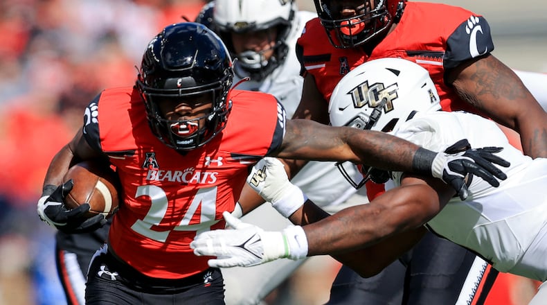 Cincinnati running back Jerome Ford (24) carries the ball as he breaks a tackle against UCF linebacker Jeremiah Jean-Baptiste, right, during the first half of an NCAA college football game, Saturday, Oct. 16, 2021, in Cincinnati. (AP Photo/Aaron Doster)