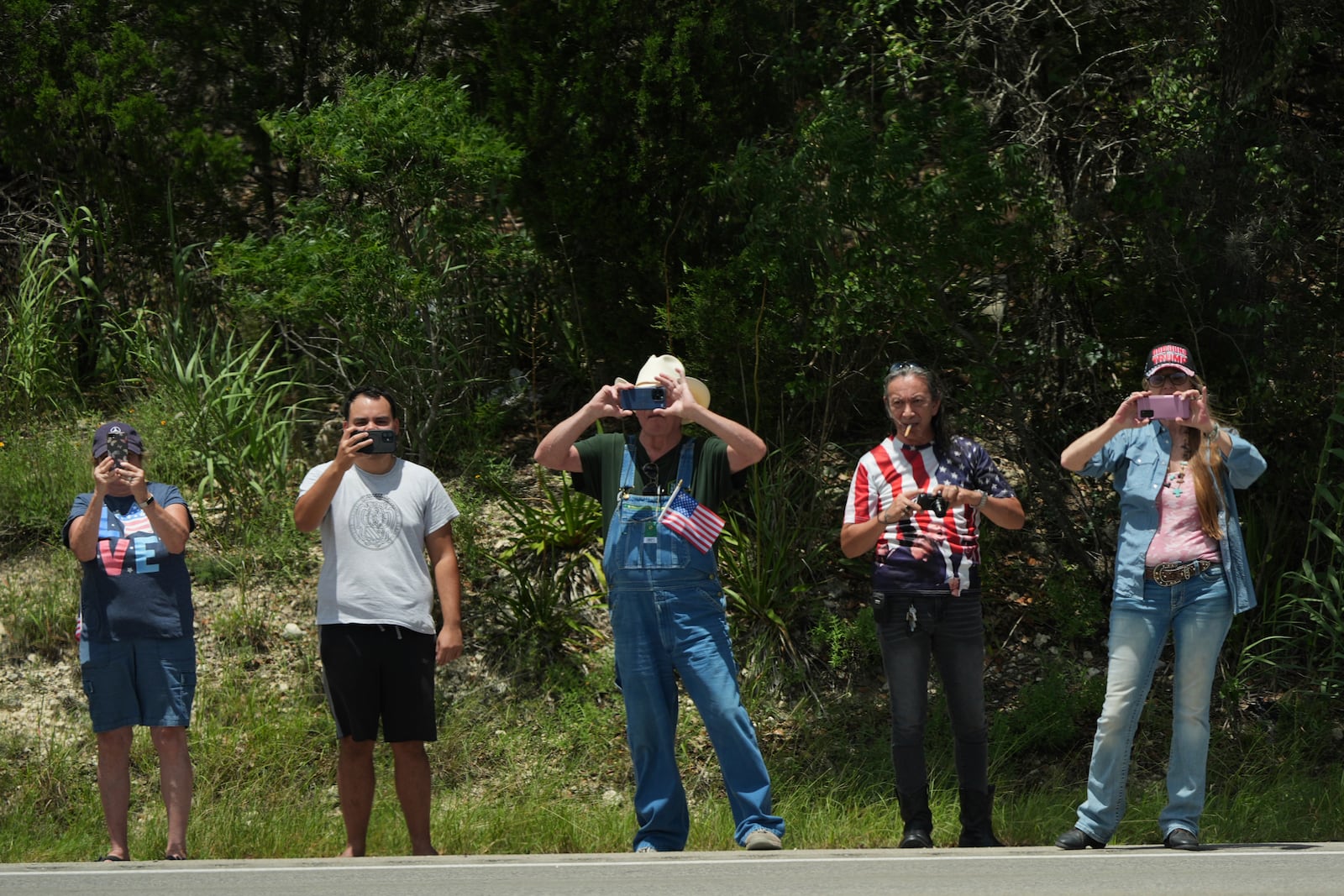 People watch as President Donald Trump and first lady Melania Trump pass in a motorcade in Kerrville, Texas, to monitor flood damage, Friday, July 11, 2025. (AP Photo/Jacquelyn Martin)