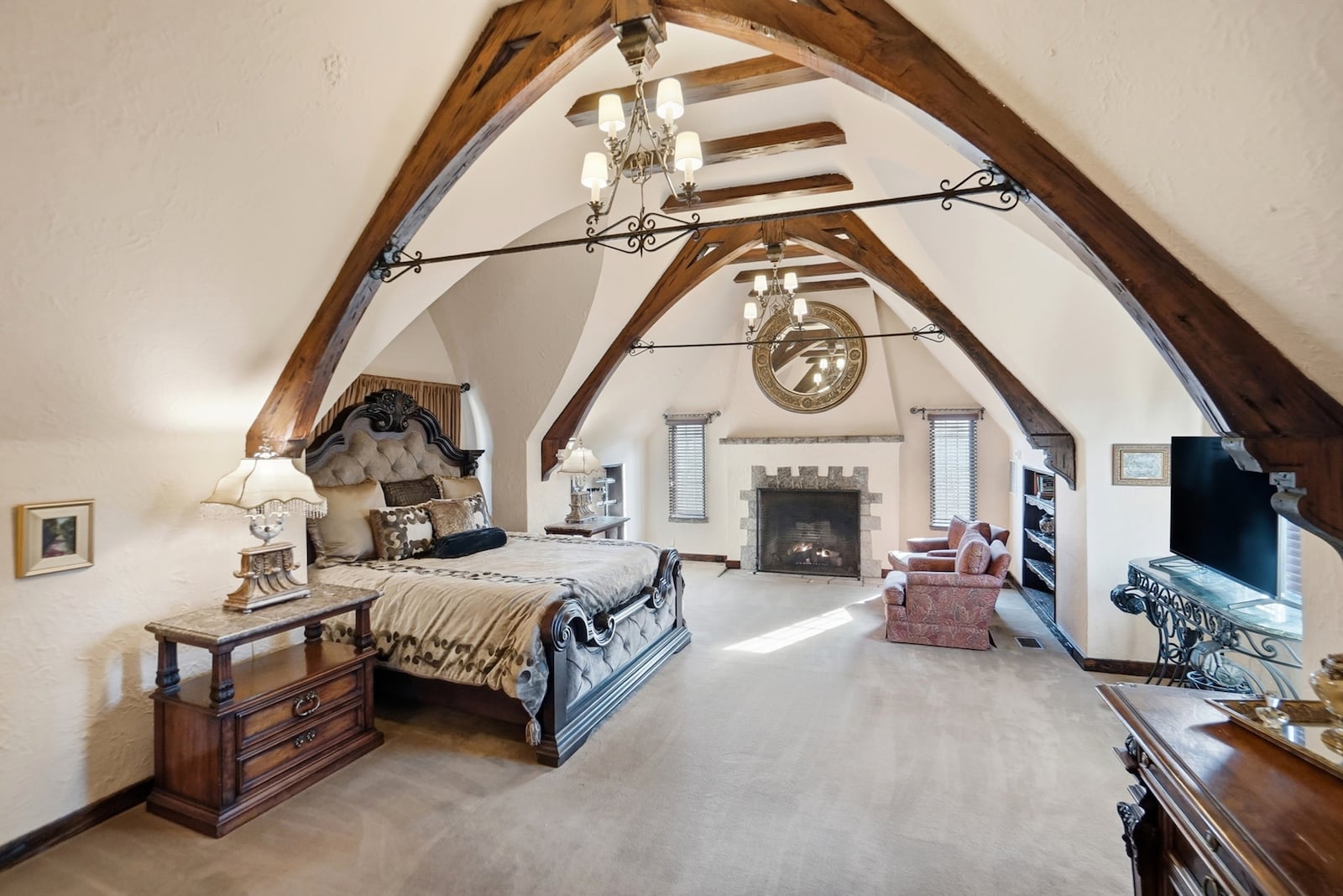 The second floor primary bedroom suite has vaulted beamed ceilings, carpeting and a woodburning fireplace. CONTRIBUTED