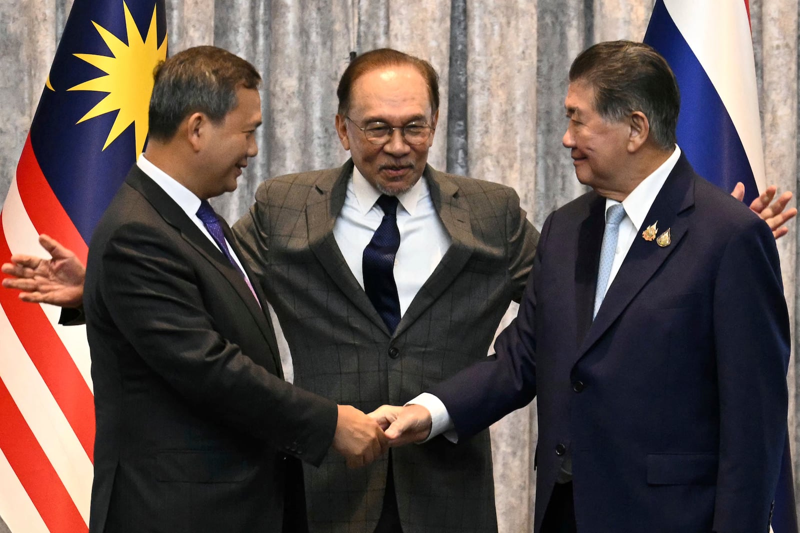 Cambodia's Prime Minister Hun Manet, left and Thailand's acting Prime Minister Phumtham Wechayachai, right shake hands as Malaysia's Prime Minister Anwar Ibrahim gestures after talks on a possible ceasefire between Thailand and Cambodia in Putrajaya, Malaysia, Monday, July 28, 2025. (Mohd Rasfan/Pool Photo via AP)