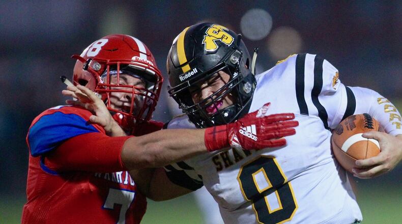 Shawnee’s Matt Guyer, right, tries to break the tackle of Northwestern’s Nathan Dewey on Friday, Sept. 20, 2019, at Taylor Field in Springfield. David Jablonski/Staff