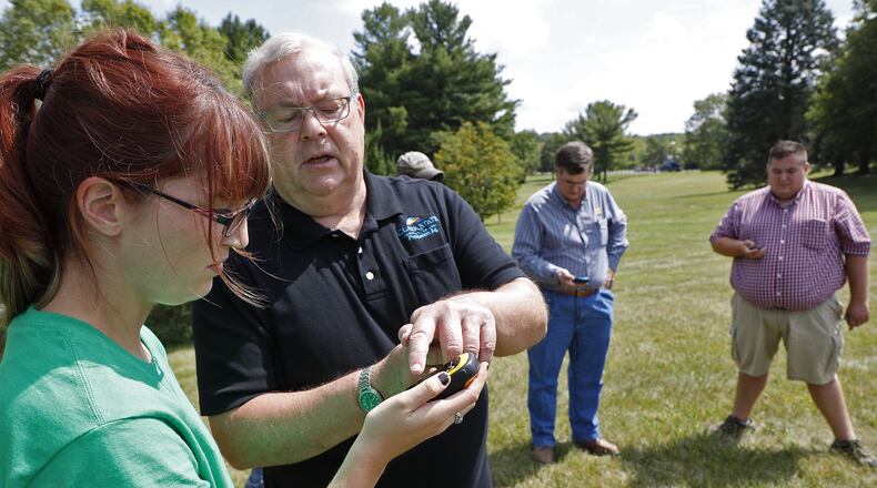 Clark State Community College instructors Larry Everett shows Lauren Queen some of the functions on a hand held GPS device as the precision agriculture class works outside Wednesday. Bill Lackey/Staff