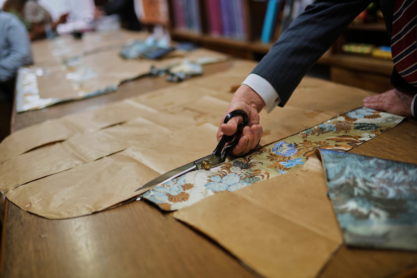 A tailor uses a pattern to cut fabric at the Gammarelli ecclesiastic clothes tailor shop in Rome, Wednesday, April 30, 2025. (AP Photo/Francisco Seco)
