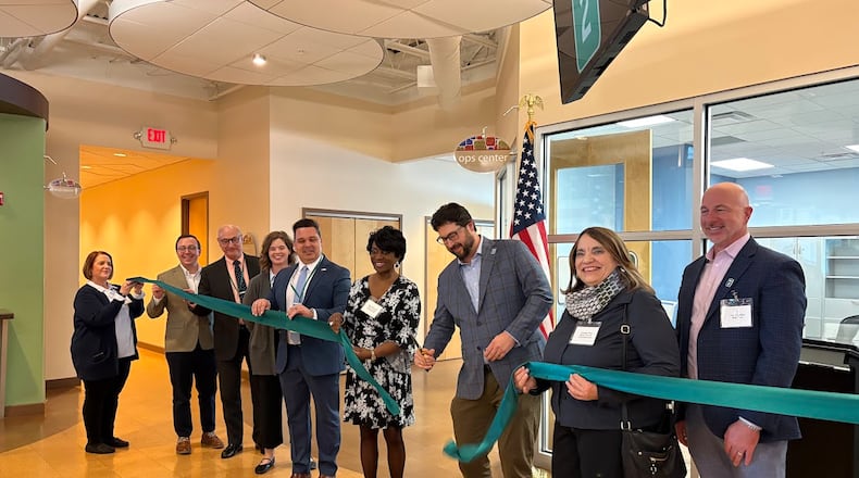 Mile Two co-founder and CEO Jeff Graley, center, cuts the ribbon with friends and colleagues at his company's new Springfield Street offices Thursday Jan. 29 in Riverside. THOMAS GNAU/STAFF