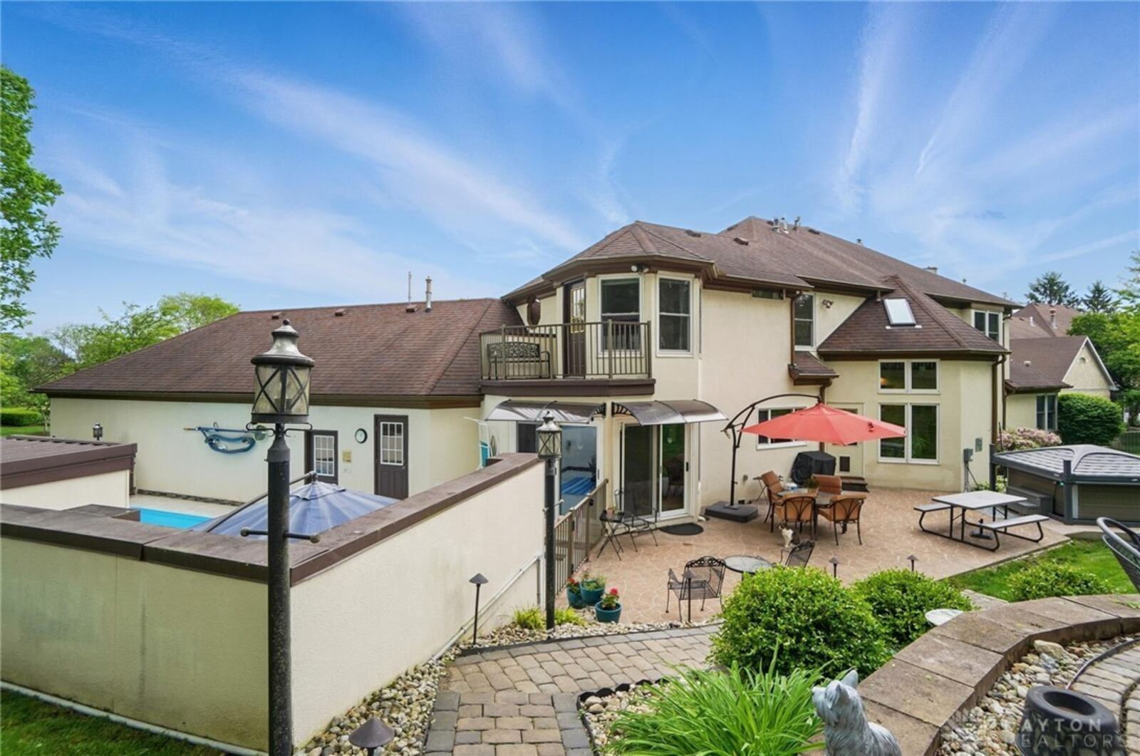 The rear of the home features an inground pool surrounded by a concrete privacy fence, brick paver pathways and a stamped concrete patio with hot tub with hard cover.