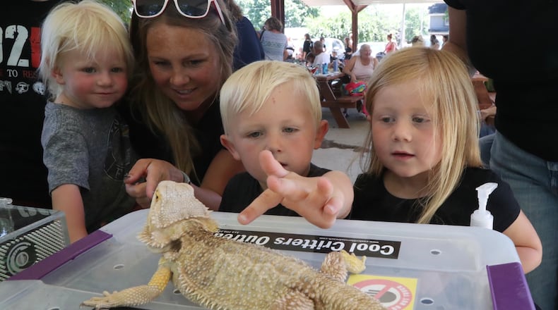 Barrett and Tinley Dinson pet a bearded dragon as Amy and Thor Circle wait their turn Thursday, June 30, 2022 during the Cool Critters Outreach program at Smith Park in New Carlisle. The program was sponsored by the New Carlisle Library. BILL LACKEY/STAFF