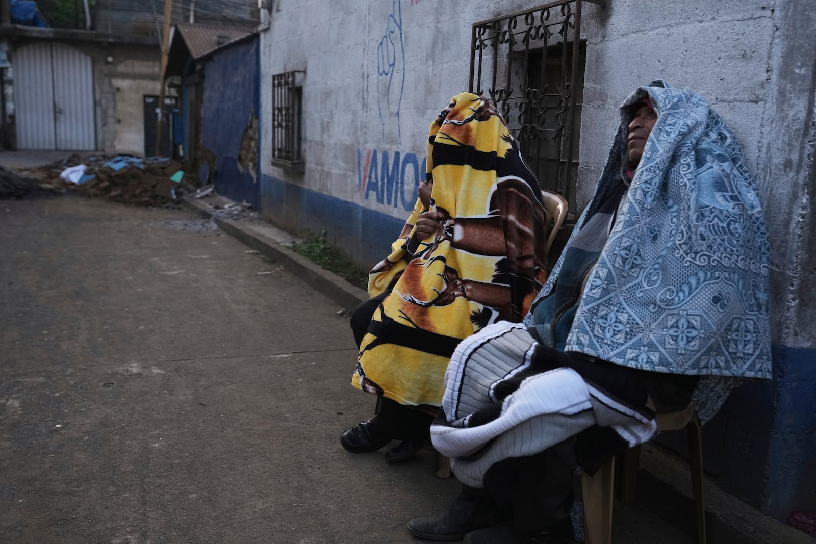 Residents sit outside their homes after dozens of earthquakes and aftershocks were recorded in a matter of hours in Palin, Guatemala, early Wednesday, July 9, 2025. (AP Photo/Moises Castillo)