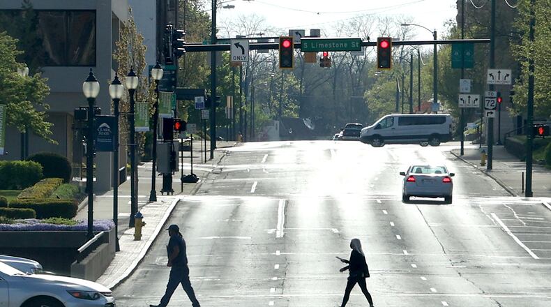 A man and woman are silhouetted as they cross High Street while it glows in the early morning sun Tuesday. BILL LACKEY/STAFF