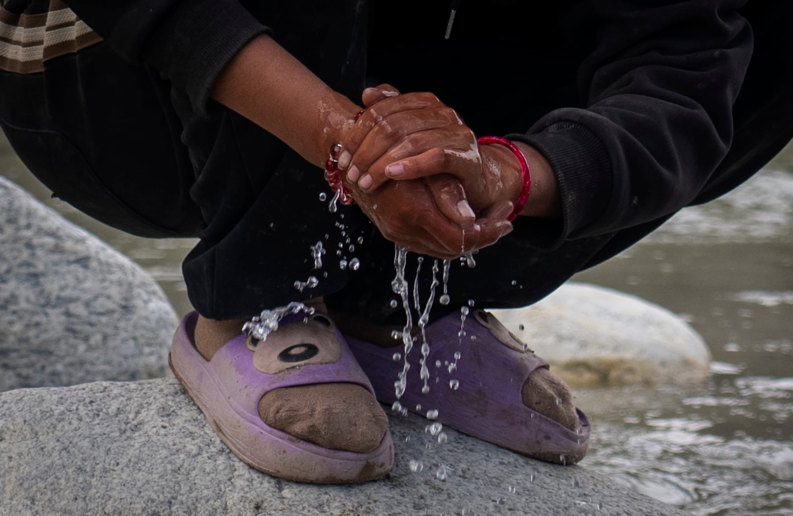 A woman washes her hands in a river at the newly relocated settlement of the abandoned Samjung village in the Mustang region, 462 kilometers (288 miles) west of Kathmandu, Nepal, Friday, April 18, 2025. (AP Photo/Niranjan Shrestha)