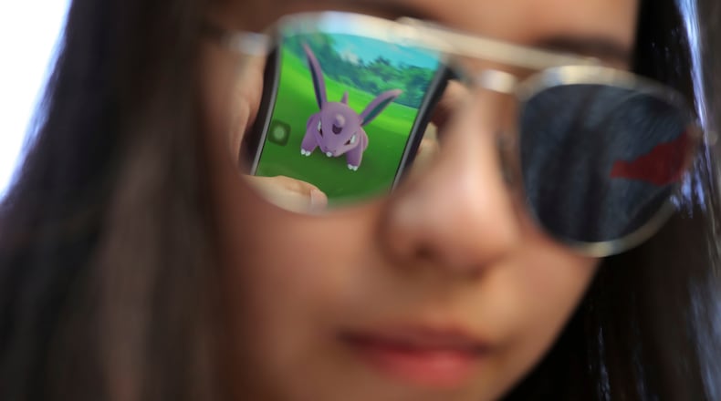 FILE - A mobile screen is reflected on a fan's sunglasses as she plays "Pokemon Go" in Hong Kong, on July 25, 2016. (AP Photo/Kin Cheung, File)