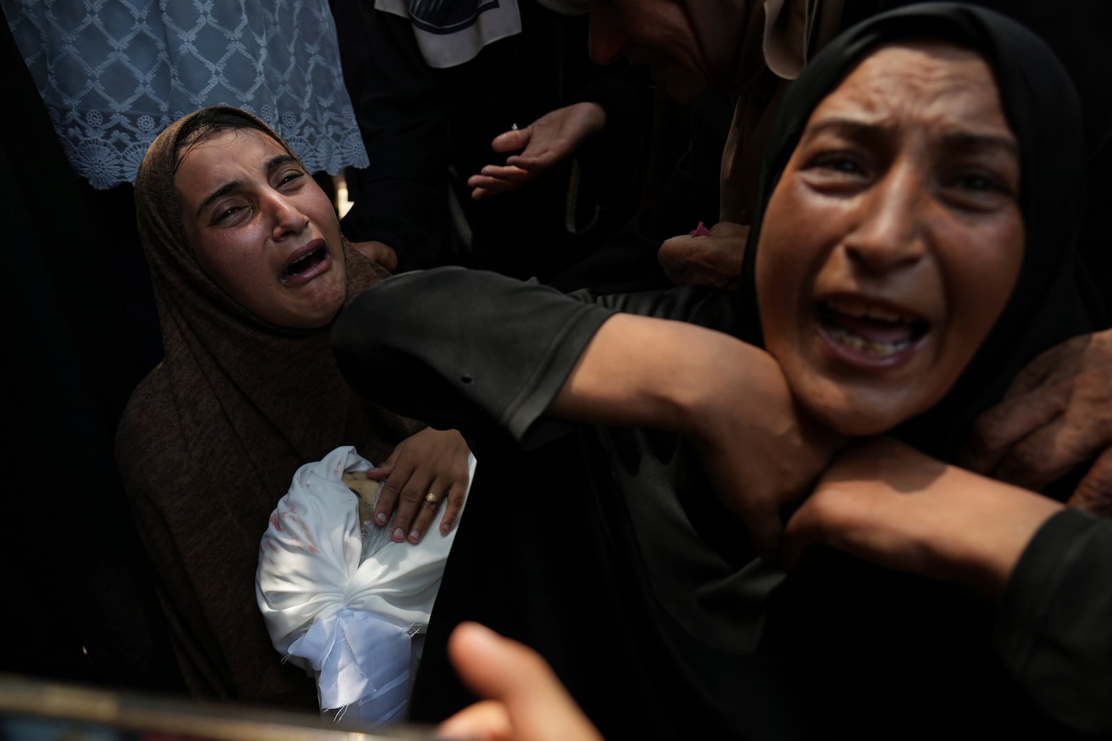 Maysara Adwan, left, mourns as she holds the body of her 11-year-old son, Qais, who was killed in an Israeli airstrike on a school in Gaza that have been used as a shelter, during his burial at Al Shifa Hospital in Gaza City, Friday, July 25, 2025. (AP Photo/Abdel Kareem Hana)