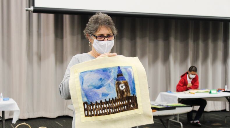 Educator Annette Eshelman holds a work displaying Big Ben in London, England, created by one of the Project Jericho students during the group's latest project. This and other works can be viewed in the windows of Springfield's Stella Bleu Bistro throughout December. Courtesy photo