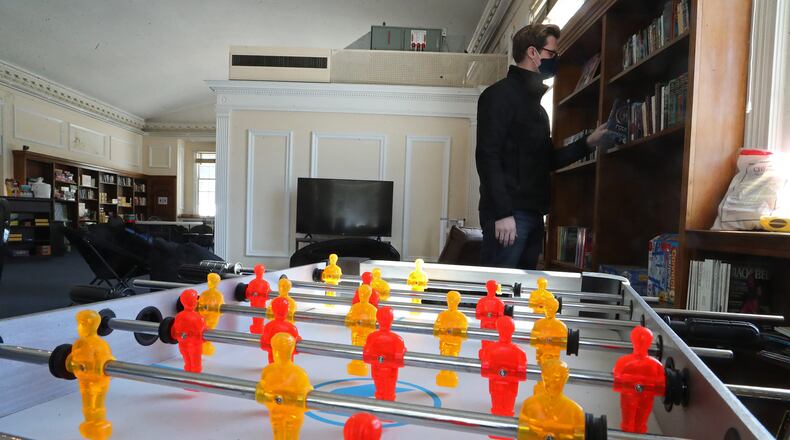 Justin Weller, executive director of the Urbana Youth Center, puts a book back on a shelf in the hang out area in the Youth Center. BILL LACKEY/STAFF