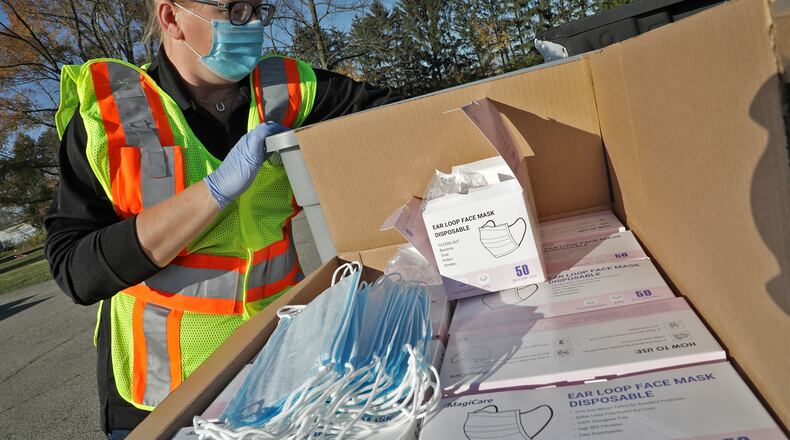 Michelle Clements-Pitstick, director of the Clark County EMA, gets masks out for the driver of a car during the free mask give away at Enon Park on Thursday. BILL LACKEY/STAFF