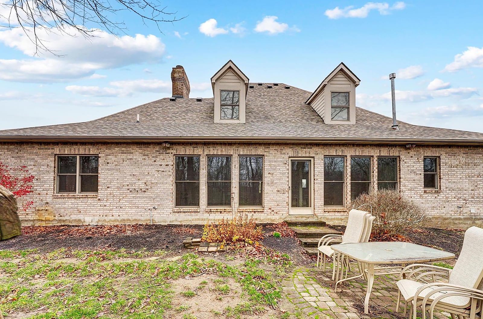 The rear of the home has a paver patio and views of the woods and creek beyond.