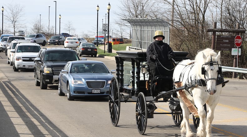 A long procession of cars slowly follows a horse-drawn hearse, carrying the body of Melvin Belle, 16, through the streets of Springfield to Ferncliff Cemetery Tuesday, March 29, 2022. Belle was shot and killed on South Yellow Springs Street this month. BILL LACKEY/STAFF