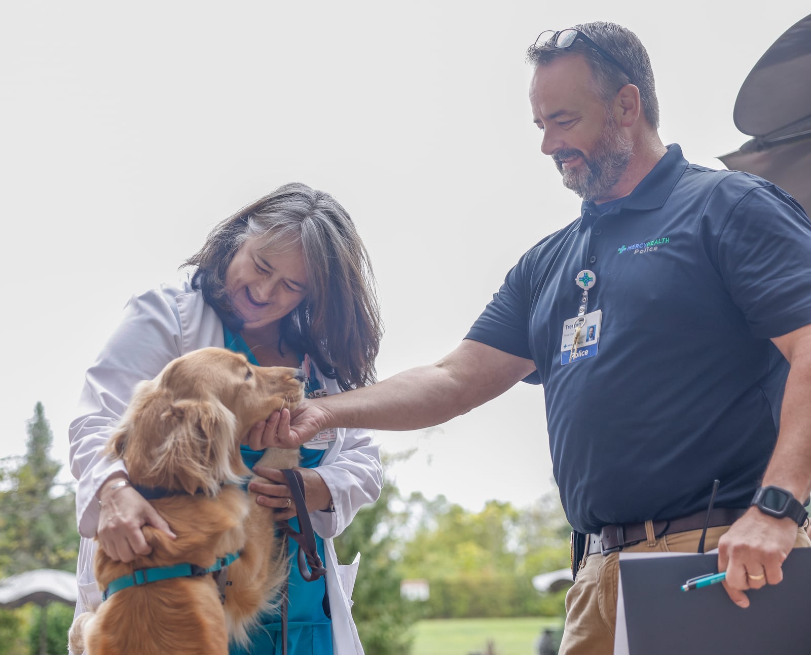 Nancy Schmelzer, left, PMHNP-BC, and Chief Trenton Brown, greet Beau, a new therapy dog, on Wednesday, Oct. 15, 2025, at Mercy Health Springfield. JOSEPH COOKE/STAFF
