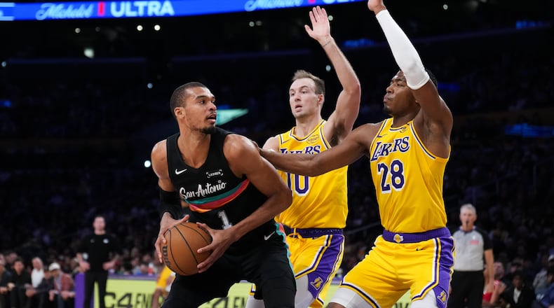 San Antonio Spurs forward Victor Wembanyama (1) is double-teamed by Los Angeles Lakers forward Rui Hachimura (28) and guard Luke Kennard (10) during the first half of an NBA basketball game Tuesday, Feb. 10, 2026, in Los Angeles. (AP Photo/Jae C. Hong)