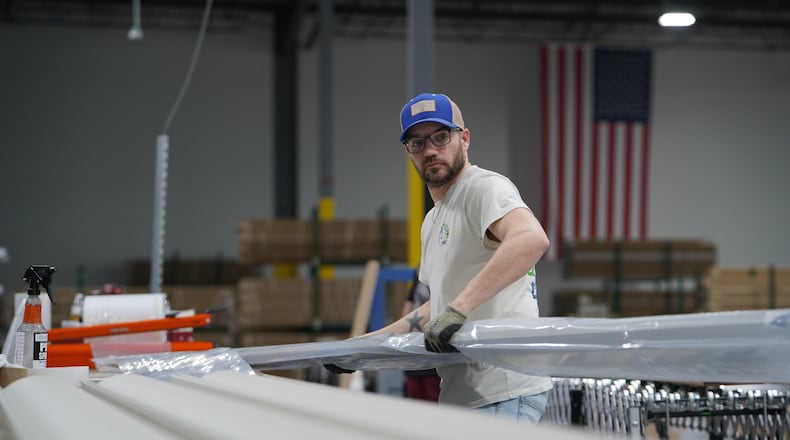 A worker lifts an aluminum beam on the factory floor at The Luxury Pergola, a company that manufactures aluminum pergolas, on Friday, Feb. 20, 2026, in Noblesville, Ind. (AP Photo/Obed Lamy)