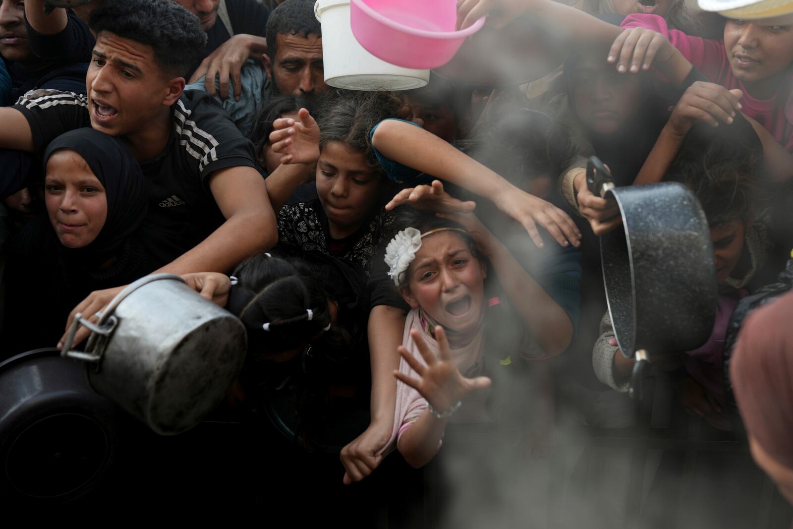 FILE.- A Palestinian girl struggles as she and others try to get donated food at a distribution center in Beit Lahiya, northern Gaza Strip, Sunday, March 16, 2025. (AP Photo/Abdel Kareem Hana,File)