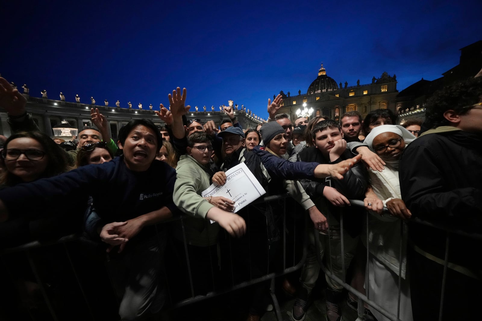 Copies of the Vatican paper L'Osservatore Romano are distributed after a rosary prayer for the late Pope Francis, in St. Peter's Square at the Vatican, Monday April 21, 2025. (AP Photo/Alessandra Tarantino)