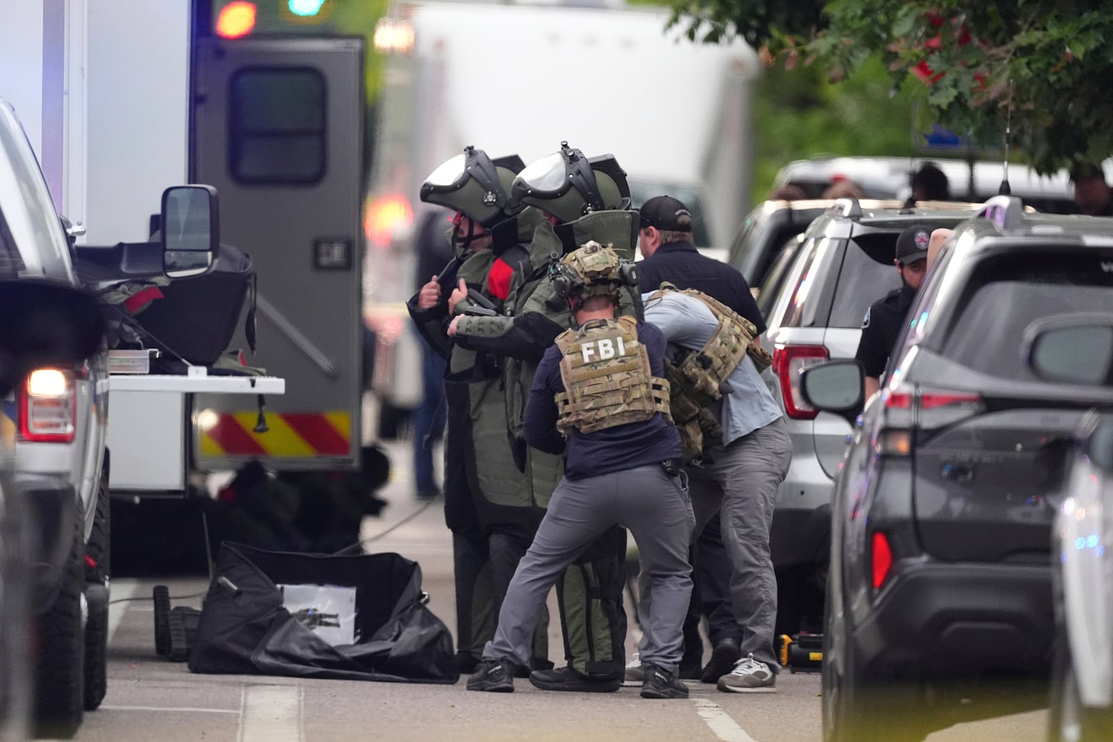 Law enforcement officials dress in protective gear to investigate after an attack on the Peark Street Mall Sunday, June 1, 2025, in Boulder, Colo. (AP Photo/David Zalubowski)