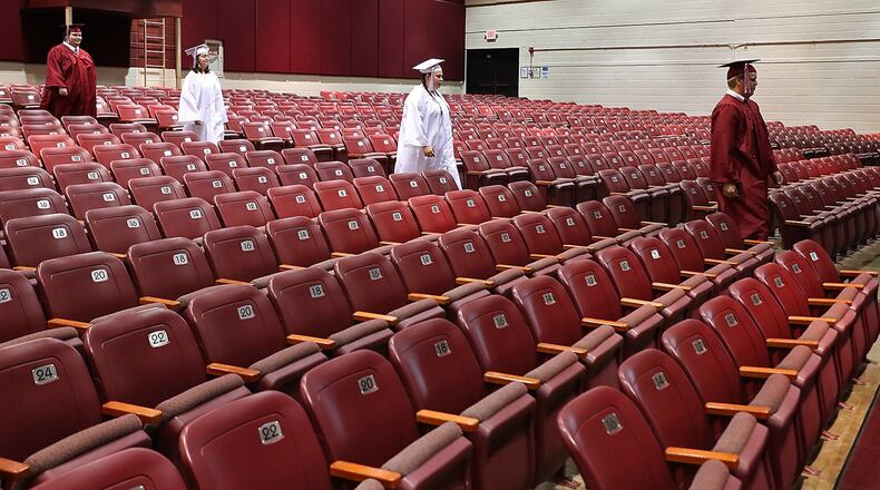 Members of the Urbana High School Class of 2020 march down the isle in an empty auditorium Tuesday. Video was taken of the students marching in their cap and gown to be edited together for a virtual graduation ceremony since they couldn’t have a real ceremony due to the coronavirus. BILL LACKEY/STAFF