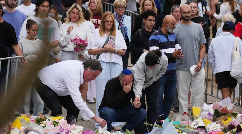 People weep and offer flowers at a floral memorial for victims of Sunday's shooting at the Bondi Pavilion at Bondi Beach on Tuesday, Dec. 16, 2025, in Sydney, Australia. (AP Photo/Mark Baker)