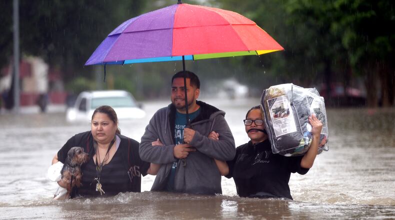 Felix Yanez, center, helps Lucy Olvio, right, and Judy wade through floodwaters as they evacuate from their flooded apartment complex Monday, April 18, 2016, in Houston. Storms have dumped more than a foot of rain in the Houston area, flooding dozens of neighborhoods and forcing the closure of city offices and the suspension of public transit. (AP Photo/David J. Phillip)