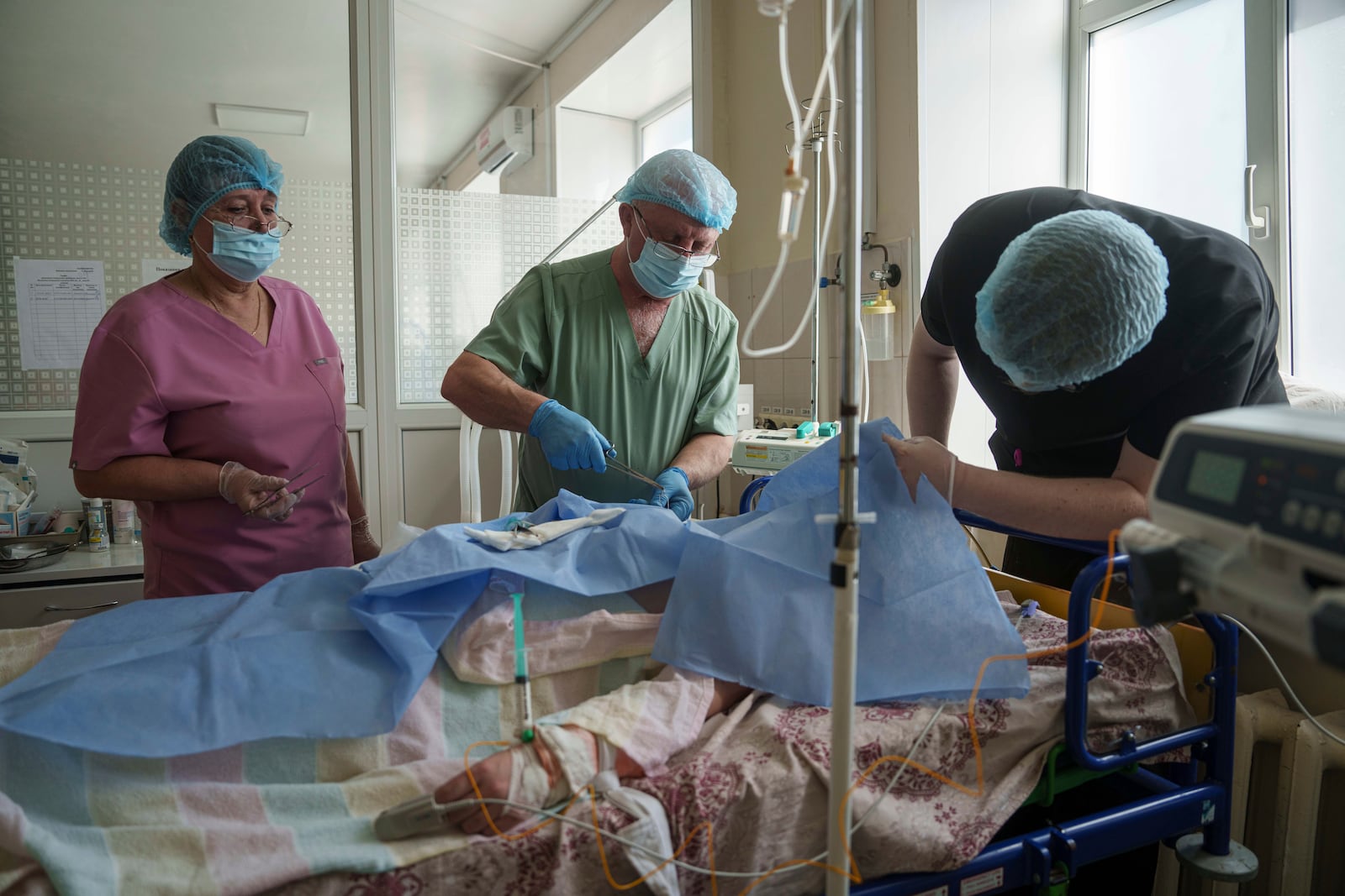 Dr. Oleksandr Zaitsev treats a patient injured in a deadly Palm Sunday Russian attack on Sumy on April 13, at a hospital ICU in Sumy, Ukraine, Tuesday, April 15, 2025. (AP Photo/Evgeniy Maloletka)