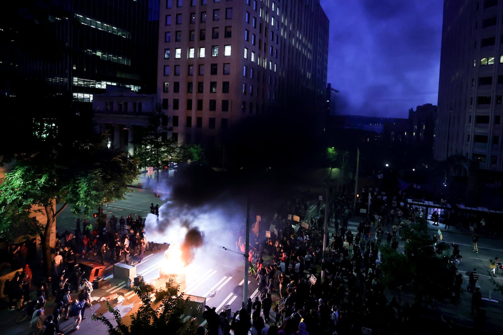 Protestors surround a dumpster that was set on fire in front of the Henry M. Jackson Federal Building during a protest against federal immigration arrests, Wednesday, June 11, 2025, in Seattle. (AP Photo/Ryan Sun)