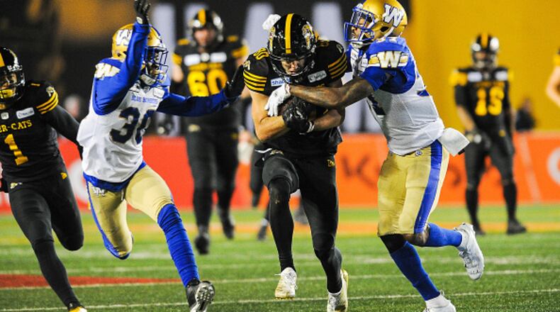 CALGARY, AB - NOVEMBER 24: Jaelon Acklin #80 of the Hamilton Tiger-Cats runs the ball against Brandon Alexander #37 (R) and Winston Rose #30 of the Winnipeg Blue Bombers during the 107th Grey Cup Championship Game at McMahon Stadium on November 24, 2019 in Calgary, Alberta, Canada. (Photo by Derek Leung/Getty Images)