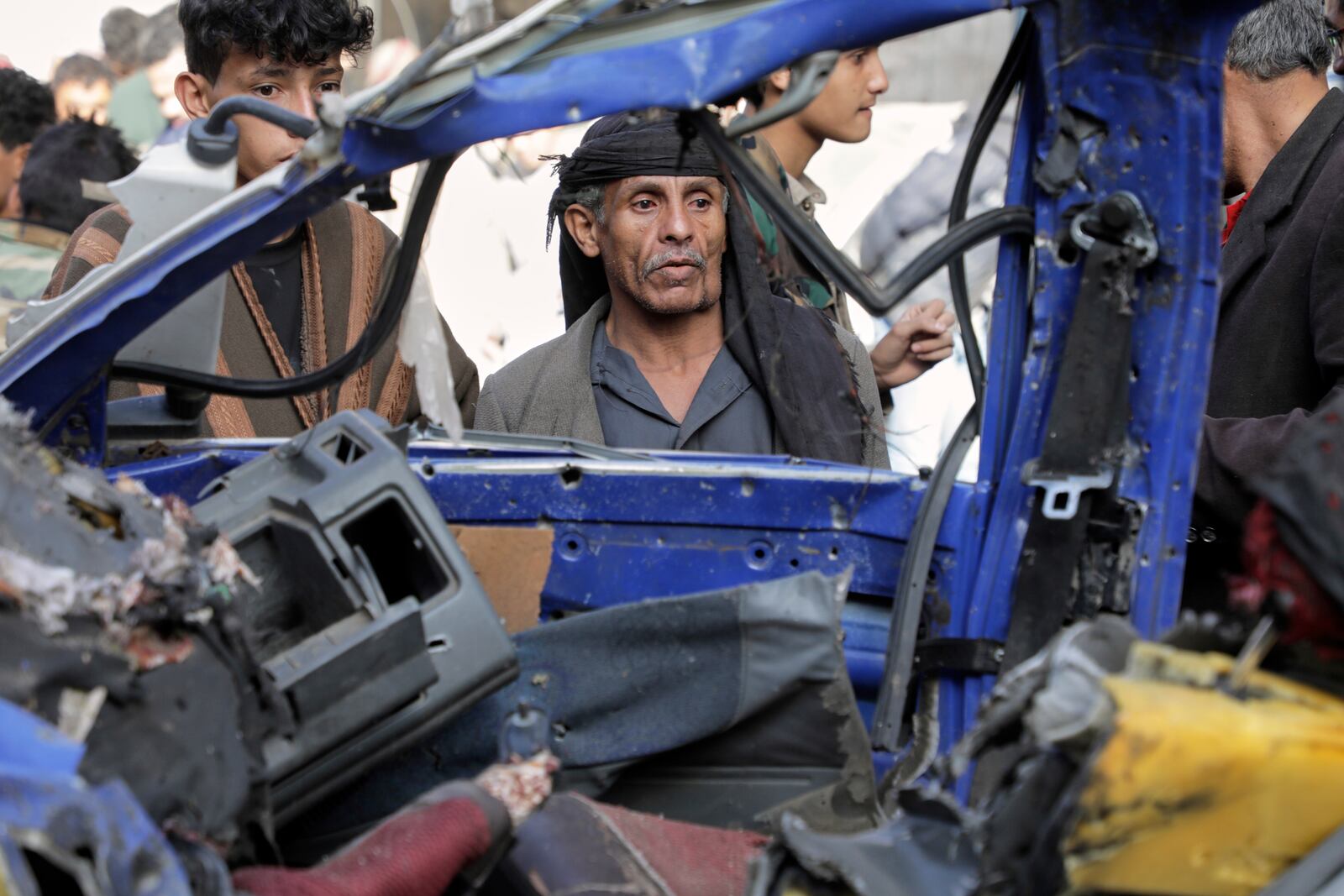Yemenis watch a damaged vehicle at Farwah popular market, which Houthis said it was struck by U.S. airstrikes in Sanaa, Yemen, Monday, April 21, 2025. (AP Photo)