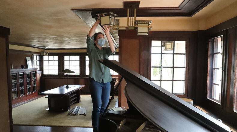 Marta Wojcik, Executive Director and Curator of the Westcott House, cleans a light fixture as she and a handfull of volunteers clean and get the house, designed and built by Frank Lloyd Wright, ready to reopen for tours on Saturday. BILL LACKEY/STAFF