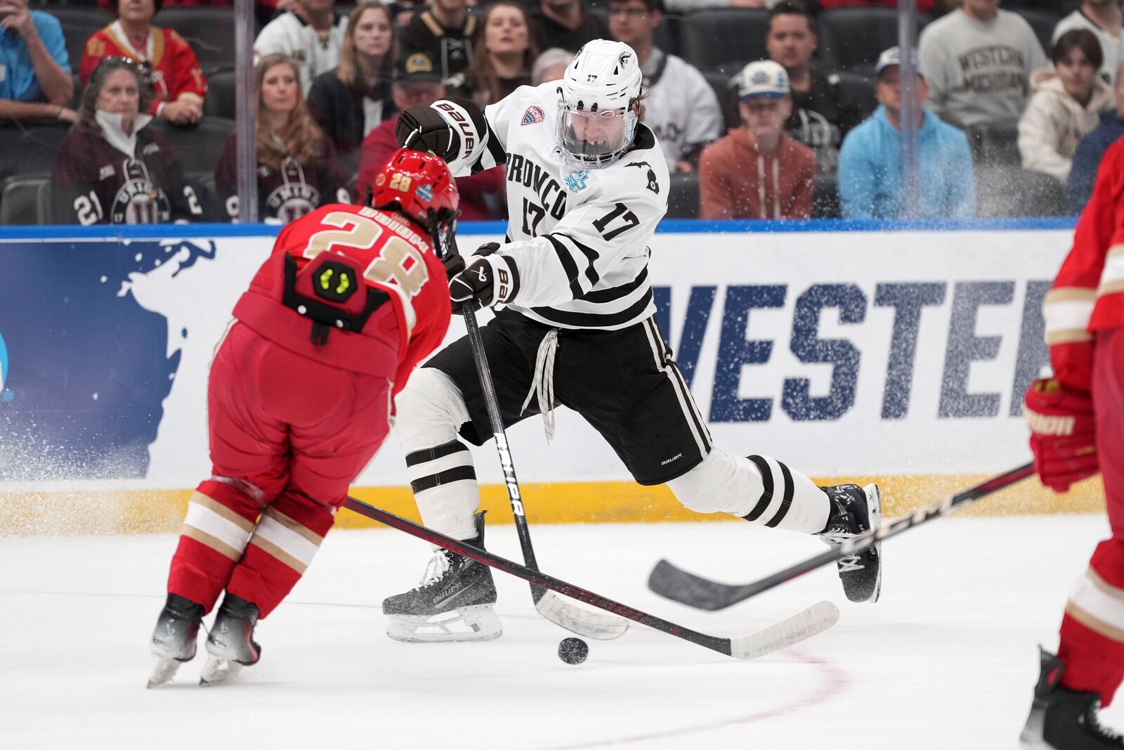 Western Michigan's Ty Henricks (17) shoots past Denver's Zeev Buium (28) during the first period in a semifinal game in the NCAA Frozen Four men's college hockey tournament, Thursday, April 10, 2025, in St. Louis (AP Photo/Jeff Roberson)