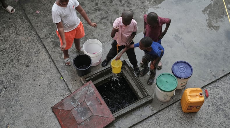 Children draw water from a reservoir at a shelter for families displaced by gang violence in Port-au-Prince, Haiti, Wednesday, Nov. 19, 2025. (AP Photo/Odelyn Joseph)