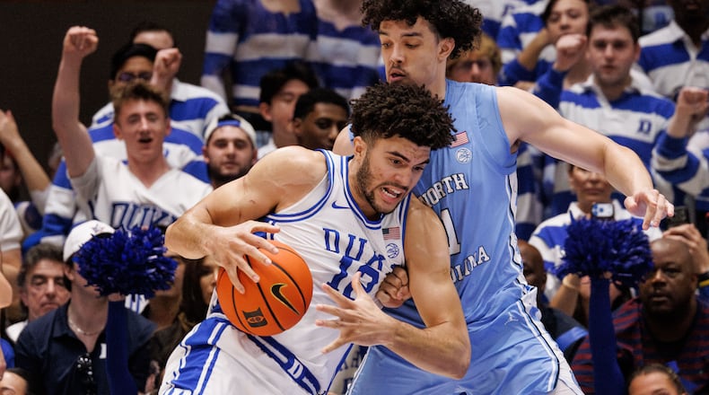 Duke's Cameron Boozer (12) handles the ball as North Carolina's Zayden High, right, defends during the first half of an NCAA college basketball game in Durham, N.C., Saturday, March 7, 2026. (AP Photo/Ben McKeown)