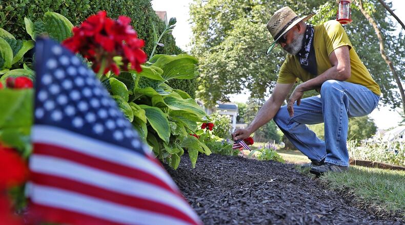 Dale Henry, president of the Gammon House, tends to the flowers in his front yard along Center Street Wednesday. BILL LACKEY/STAFF
