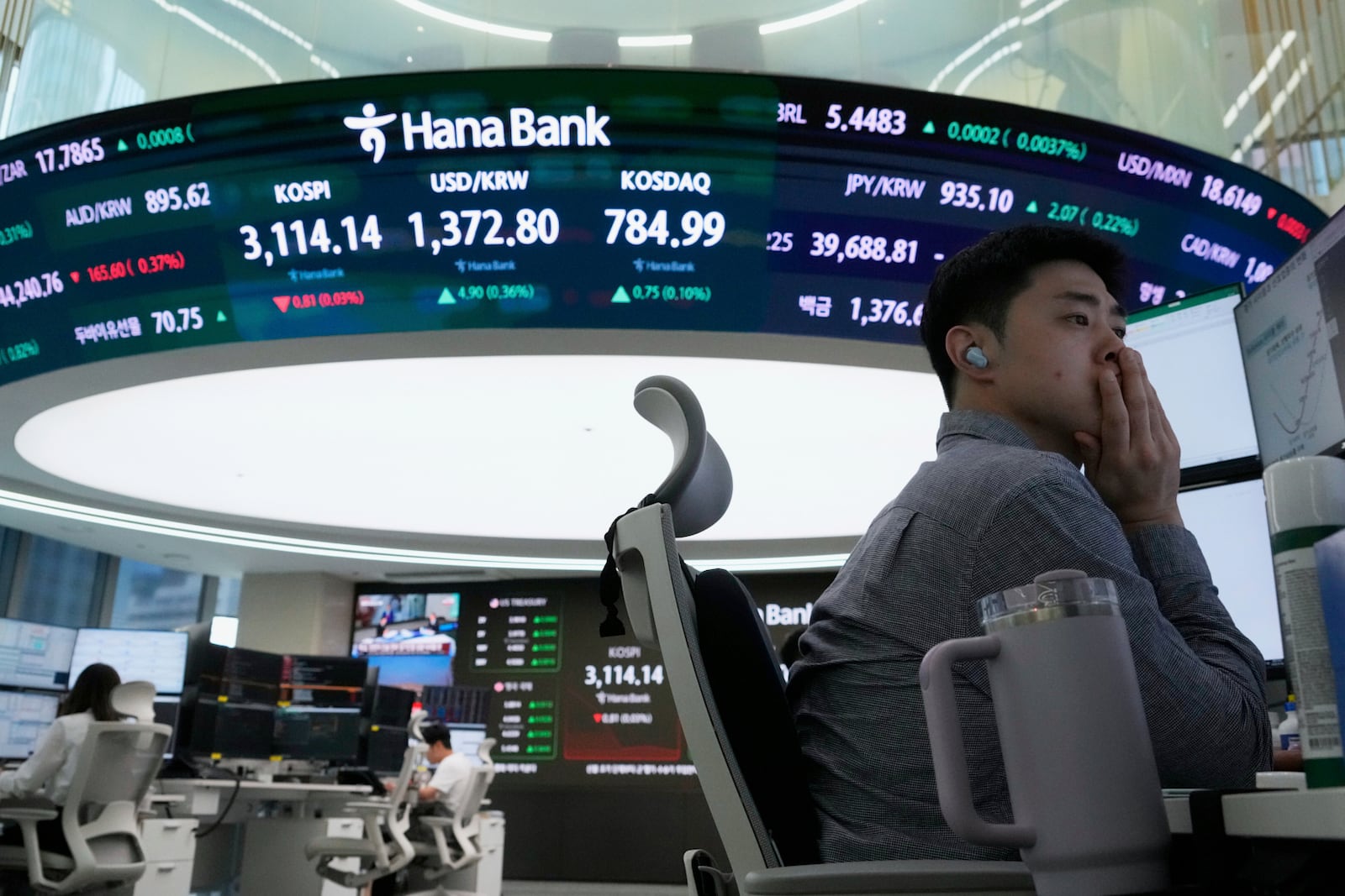 A currency trader watches monitors near a screen showing the Korea Composite Stock Price Index (KOSPI), top center left, and the foreign exchange rate between U.S. dollar and South Korean won, top center, at the foreign exchange dealing room of the Hana Bank headquarters in Seoul, South Korea, Wednesday, July 9, 2025. (AP Photo/Ahn Young-joon)